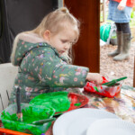 Young child getting some paint from a pot to use.
