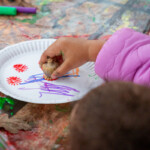 A child using a seed pod to make prints using paint.
