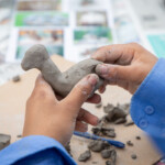Close up of a kids hands shaping some clay into an animal design.
