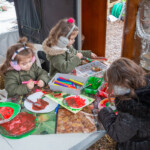 A group of three young girls painting plates. One looks like a watermelon.