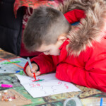 A young boy using a felt tip to colour in a picture of a bat.