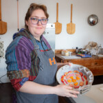 Jay holding up the lined cake tin which has an arrangement of fruits at the bottom.