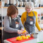 Lindsay and Val squeezing oranges so they can use the juice in one of the recipes.
