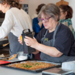 A member of the group grating orange zest over some baked bread crumbs.