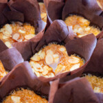 A close up shot of lots of cupcakes in brown wrappers.