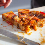 A close up of some remaining slices of cake made from a selection of danish pastries and fruits.
