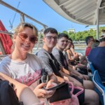 Young people and a staff member sat on the Thames Uber Boat, smiling for the camera.