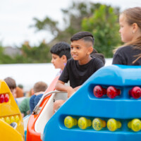 A young boy smiling while riding the merry go round at the 2024 cultural fayre.