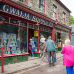 Participants entering an old fashioned supply store at St Fagans,