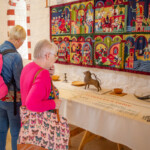 Two participants looking at a display located inside one of the old feast halls at St Fagans. There's a drinking horn and other items on the table alongside a description of how the room would be used.
