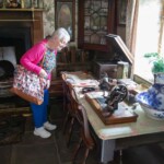 A participant leaning over a table, looking at some old sewing equipment on display in a house at St Fagans.