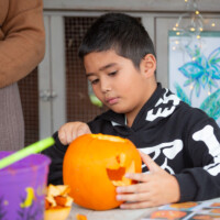 A child sat down, examining their pumpkin.