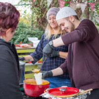 A participant helping to ladel some soup into a cup to give to a visitor.